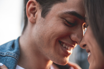 Close up focus on male face showing sincere joy to girlfriend. They are standing in front of each other and laughing with content