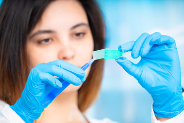 technician girl with microfluidic device LOC in microbiological lab