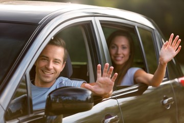Portrait of a Couple Waving Hands out of the Window of Car