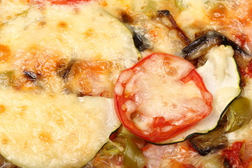 Surface of baked pizza close-up. Tomatoes, cheese, zucchini, eggplants. Food concept