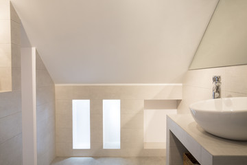 Washbasin in bright minimal bathroom interior on attic with windows. Real photo