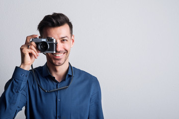 Obraz premium Portrait of a young man in a studio with a camera on front of his eye. Copy space.