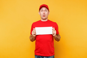 Delivery man in red uniform isolated on yellow orange background. Professional male employee courier in cap, t-shirt hold white empty blank paper. Service concept. Copy space place for text or image.