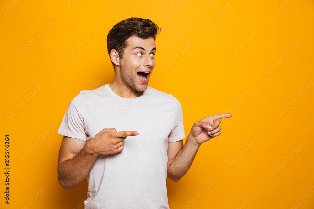 Wall mural Portrait of a joyful young man pointing fingers away