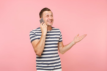 Portrait of fun emotional young man talking on mobile phone, conducting pleasant conversation isolated on trending pastel pink background. People sincere emotions lifestyle concept. Advertising area.