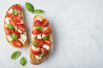 Bruschetta with tomatoes, mozzarella cheese and basil on a light background. Traditional italian appetizer or snack, antipasto. Top view with copy space. Flat lay