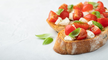 Bruschetta with tomatoes, mozzarella cheese and basil on a light background. Traditional italian appetizer or snack, antipasto. Top view with copy space. Flat lay