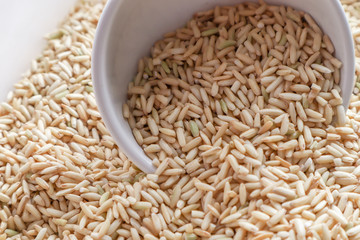 Raw brown rice in a bowl. top view food background