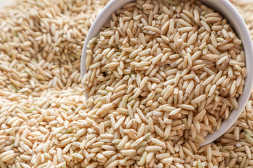 Raw brown rice in a bowl. top view food background
