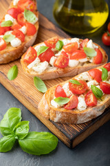 Bruschetta with tomatoes, mozzarella cheese and basil on a cutting board. Traditional italian appetizer or snack, antipasto