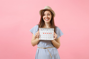 Portrait of young woman in blue dress, hat holding periods calendar for checking menstruation days isolated on bright trending pink background. Medical, healthcare, gynecological concept. Copy space.