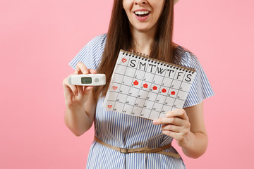 Smiling woman in dress hold in hand thermometer, female periods calendar for checking menstruation days isolated on pink background. Medical healthcare, ovulation gynecological concept. Copy space.