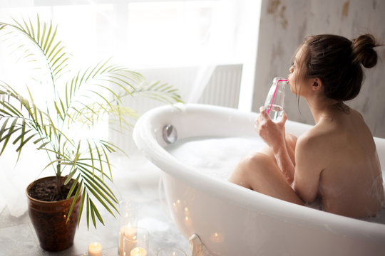 pleasant woman taking pleasure in bath with juice. back view photo
