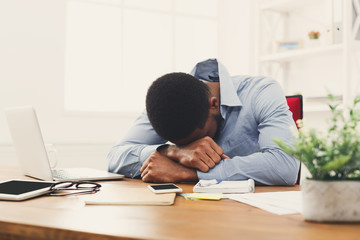 Fototapeta na wymiar Sleeping overworking black businessman with laptop