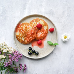 Pancakes with sweet jam, fresh berries and mint leaves on concrete table. Top view. 