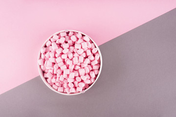 Colorful marshmallow laid out on pink and gray paper background. pastel creative textured pattern. minimal style.