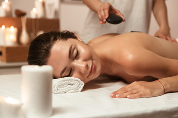 Obraz na płótnie Canvas beautiful young woman having hot stone massage