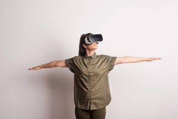 Portrait of a young beautiful woman with VR goggles in studio.