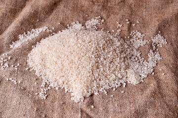 Raw rice is scattered on sackcloth. Uncooked food. selective focus