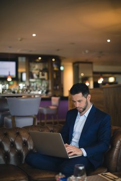 Businessman working on laptop while sitting indoors