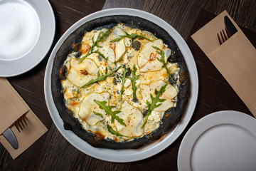 Black four cheese pizza served on the table in restaurant. Quattro formaggi pizza with pears on black dough top view