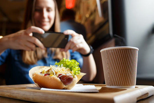Young woman taking photo of her lunch in cafe or restaurant.