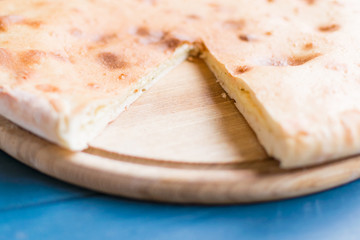 Pie with cheese, khachapuri on a blue wooden background.