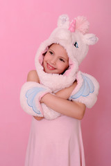  little girl in a hat with  unikorn  on a pink background.