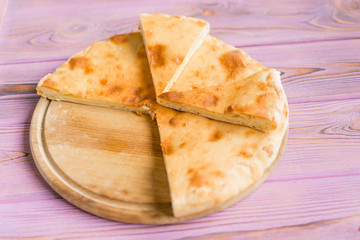 Pie with cheese on a wooden pink background. Khachapuri - flat cake with cheese.