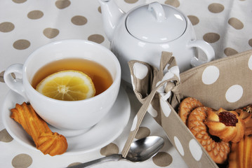 tea with lemon and sweet cookie in a white cup with a slice of lemon