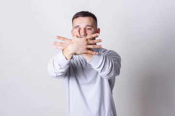 Young handsome man showing hands gesture like butterfly or bird on grey background, copy space. Portrait man in white turtleneck