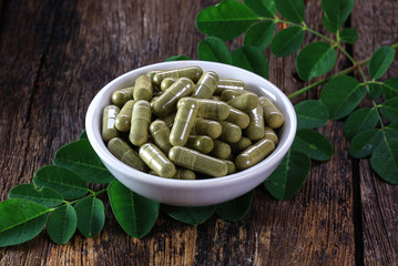 Herbal capsules from moringa leaf in white cup