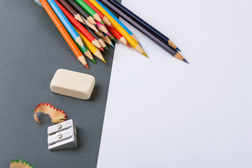 Fototapeta premium Color pencils on a gray background with a white sheet ready for drawing