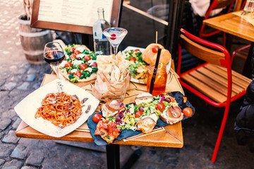 Restaurant table setting with food outdoor on the street. Italian pasta spaghetti, glass of red...