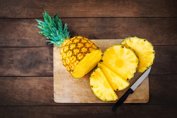 Pineapple on wood texture background. Whole and sliced tropical pineapple on wooden cutting board  with copy space. Flat lay
