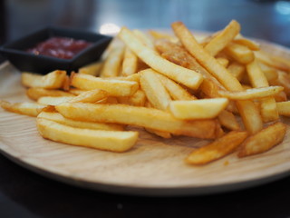 Fresh fried french fries with ketchup on wooden dish