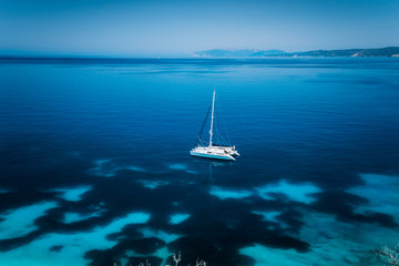 Fteri beach Kefalonia, Greece. White catamaran yacht in clear blue transparent sea with dark pattern water surface