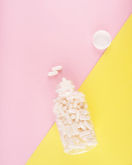 White pills isolated on pastel coloured background. Medication and prescription pills flat lay background.