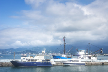 Yachts and fishing boats on the wharf in the port on a summer day.