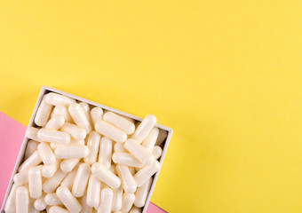 White pills isolated on pastel coloured background. Medication and prescription pills flat lay background.