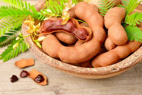 tamarind fruits and fresh leaves on the wooden board