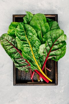 Fresh raw swiss rainbow chard leaves on gray stone background.