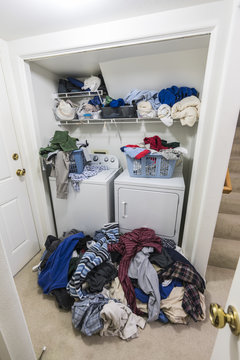 Messy Laundry Room Vertical View With Piles Of Clothes Needing To Be Washed.  