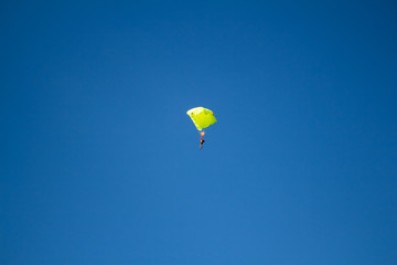 Man, a paratrooper is flying through the blue sky amidst white clouds on a parachute