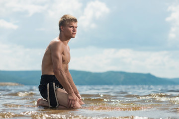 Man meditates on the beach after a workout.