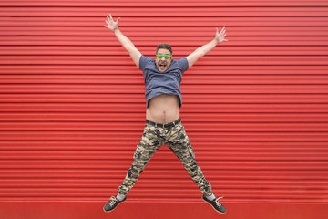 Happy modern man jumping on red background
