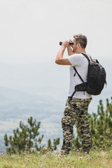 Man enjoying the nature and looking through binoculars