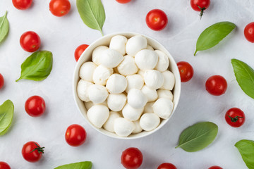 Basil, tomatoes and mozzarella in bowl for caprese salad, italian food and mediterranean diet concept on a light background. Top view. Flat lay