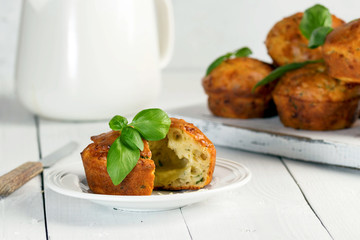 Homemade freefly baked double cheese muffins with basilic on a white wooden board. Healthy snack or breakfast meal.