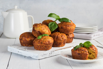 Homemade freefly baked double cheese muffins with basilic on a white wooden board. Healthy snack or breakfast meal. Concept of healthy eating in pure tones.